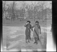 Two women ice skate on a frozen pond, Boston, 1914