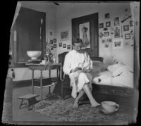 H. H. West sits on his sister's bed holding a doll, Los Angeles, about