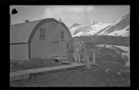 Three servicemen pose on the wood slat walkway outside the barracks, Dutch Harbor, 1943