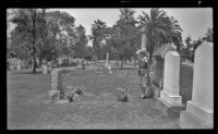 Mertie West stands by the decorated graves of Mr. and Mrs. George Miller West in Evergreen Cemetery on Decoration Day, Los Angeles, 1943