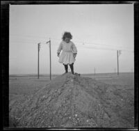 Elizabeth West stands on a pile of sand, Venice, about 1905