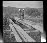 Elizabeth and Frances West tossing pumice stones into Owens River from a bridge, Mono County, circa 1915