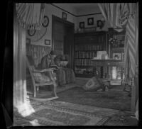 Wayne West sits on a couch reading a book, Los Angeles, about 1901