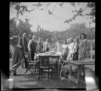 Members of the West, Shaw and McDonald families pose around a picnic table in the McDonalds' backyard, Burbank, 1948