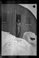 Fellow serviceman of H. H. West, Jr. flips through a book while standing in the doorway of his quarters, Dutch Harbor, 1943