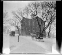 Horse-drawn carriages drive past the East Ward School, Red Oak, 1917