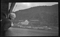 Mertie West looking over a ship's rail at a large gold mine, Juneau, 1946