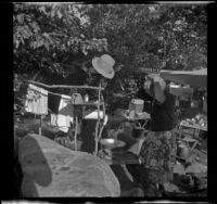 Mertie West fixing her hair in the campsite, Mono County, 1941