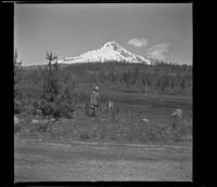 H. H. West poses in front of Mount Hood, Government Camp, 1942