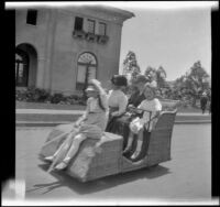 Elizabeth West, Minnie West, Christina Schmitz and Frances Cline riding an Osborn Electriquette past the Nevada Building in Balboa Park, San Diego, [about 1915]