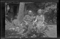 H. H. West and Mertie West sit beneath at tree at Glen Velzy's cabin, San Gabriel Mountains, 1941
