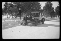 H. H. West, H. H. West, Jr., Mertie West and Frances West Wells sit around H. H. West's Buick on a snowy road, Big Bear, 1932