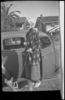 Mrs. Smith stands by a car while holding a dog's leash, Los Angeles, 1939