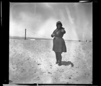 Mary Whitaker standing on the beach and pointing to the camera, Redondo Beach, 1901