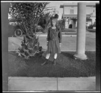 Tacoma Winkler stands on a tree lawn and poses in front of her family's home, Los Angeles, about 1918