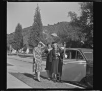 Mertie West holds open the door of a car while her step-daughter, Elizabeth Siemsen and granddaughter, Dorothea Siemsen stand behind her, Glendale, 1942