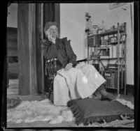 Earl Kellum wears women's attire and rolls his eyes while sitting in a rocking chair, Los Angeles, about 1899