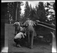 Wilfrid Cline, Jr. and Harry Schmitz working to fix a tire on Ade Bystle's Ford, Trinity County vicinity, 1917