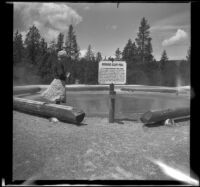 Mertie West stands at the edge of Morning Glory Pool, Yellowstone National Park, 1942