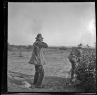 Webster Brain showing Bob Brain how to break a bottle in the air, Irwindale, about 1900