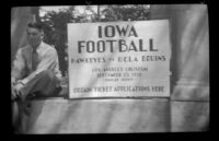 Man sits next to a sign at the Iowa Picnic in Bixby Park, Long Beach, 1938