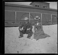 H. H. West and Mertie Whitaker sit in the sand in front of the North Beach bathhouse, Santa Monica, 1901