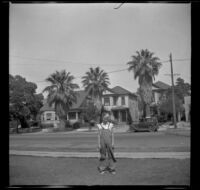 A boy stands on a lawn in front of old Quayle properties on Griffin Avenue between Manitou and Baldwin streets, Los Angeles, 1930