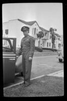 P.F.C. H. H. West, Jr. poses next to a car parked along North Ridgewood Place, Los Angeles, 1945