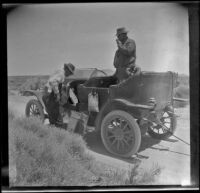 Fred Hamilton working on his car while Al Schmitz watches, Mojave vicinity, 1917