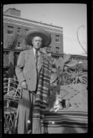 Dr. Bim Smith stands in his backyard wearing a serape and a hat, Los Angeles, 1939