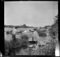 William "Babe" Bystle holds his hat out to Frances and Elizabeth West as they stand in the Sacramento River, Redding vicinity, about 1914