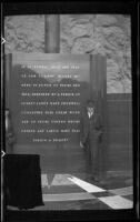 Wes Witherby poses for a photograph while standing next to an inscribed tablet, Boulder City vicinity, 1939