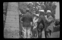 Attendees of the Iowa Picnic in Bixby Park look at a sign posted on a tree, Long Beach, 1938