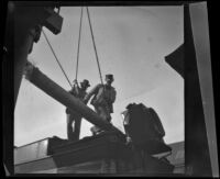 Worm's-eye view of E. L. Swaine and a worker investigating a water tank valve, Pomona, 1899