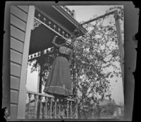 Worm's-eye view of Louise Ambrose balancing on a porch rail, Los Angeles, about 1894