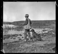 Guy M. West stands with his gun and dog at the edge of Watson Lake, Long Beach vicinity, about 1895