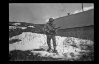 Fellow serviceman of H. H. West, Jr. poses with a rifle outside the barracks, Dutch Harbor, 1943