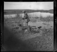 H. H. West stands with his gun and Guy West's dog at the edge of Watson Lake, Long Beach vicinity, about 1895