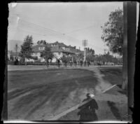 Men riding bicycles down a street, Pasadena, 1899