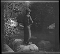 H. H. West, Jr. stands atop a small rock and fishes in Matilija Creek, Ojai vicinity, about 1925