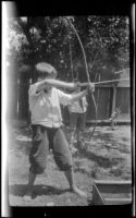 Ambrose Cline draws back a bow and arrow, Glendale, about 1924