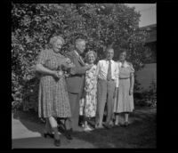 H. H. West's family poses in front of an orange tree by Wayne West's home, Santa Ana, 1941