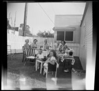 Mertie West, Eva Newquist, Rudy Newquist, Anna Newquist, Maurine Bacon, Tommie Newquist and "Punkie" Bacon pose while supping in the Bacons' backyard, Los Angeles, 1948