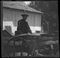 Charlie Mertz sitting with drying apricots, Santa Ana, about 1899