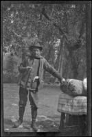 H. H. West poses next to bundled camp bedding, Yosemite National Park
