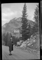 Mertie West stands in the road and poses in front of a sign for the Kicking Horse Tea Room, Field vicinity, 1947