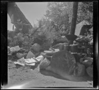 Mertie West, wife of H. H. West, sits on a rock next to their camping stove, Toms Place, 1942