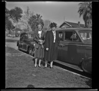 Mertie West and Josie Shaw stand next to a car parked outside the West's residence, Los Angeles, 1944