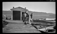 Forrest Whitaker tinkers with a piece of equipment while Ann West watches, Big Bear Lake, 1946