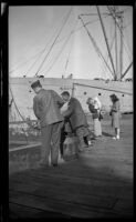 Men fishing off the pier with the Aleutian anchored in the background, Cordova vicinity, 1946